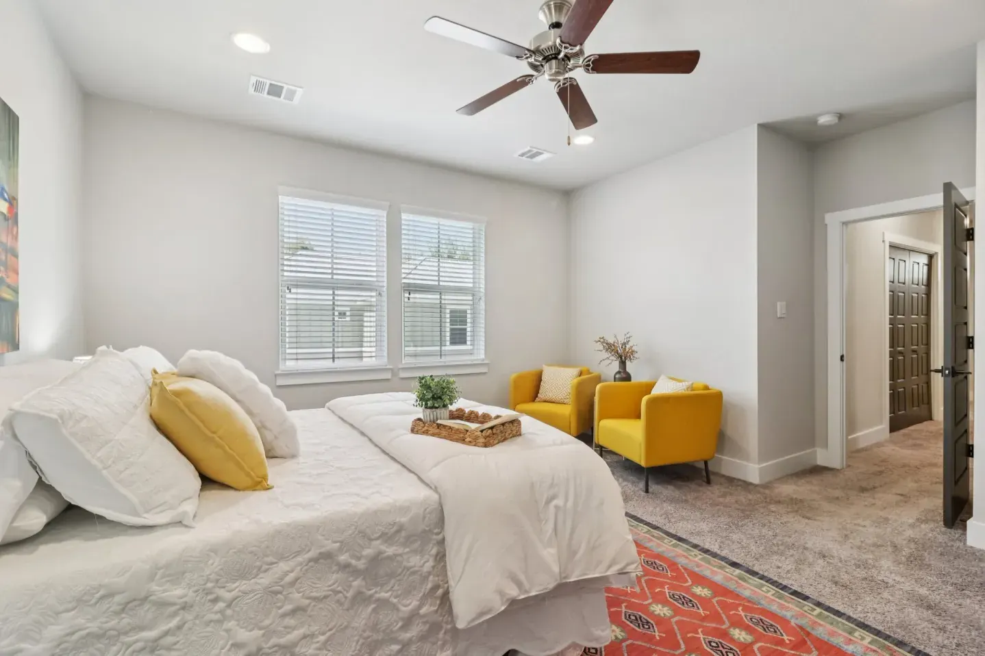 Bedroom staged with yellow chair and soft neutral bedding
