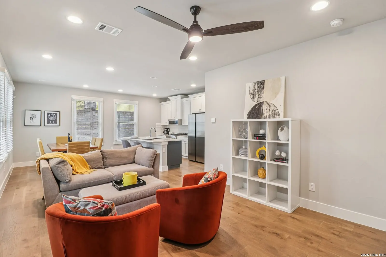 Open living room staged with orange accent chairs and neutral seating