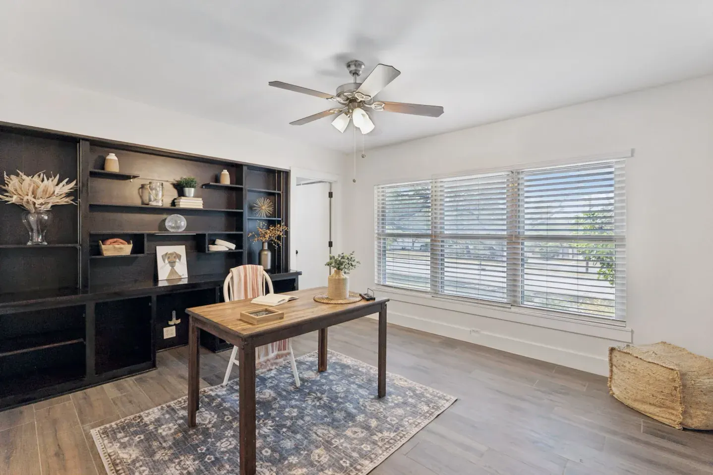 Home office staged with black shelving and a central desk